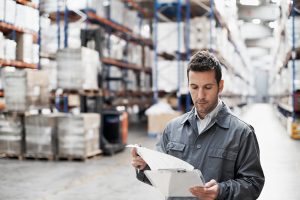 Handsome warehouse worker doing a stocktake while in a warehouse