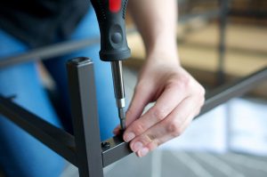 Horizontal close up of hands screwing together furniture pieces